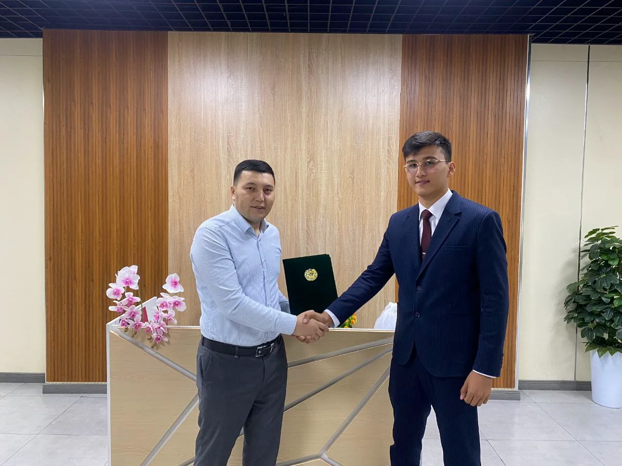 REAL EXAMS and Registan LC representatives shaking hands over the signed agreement.